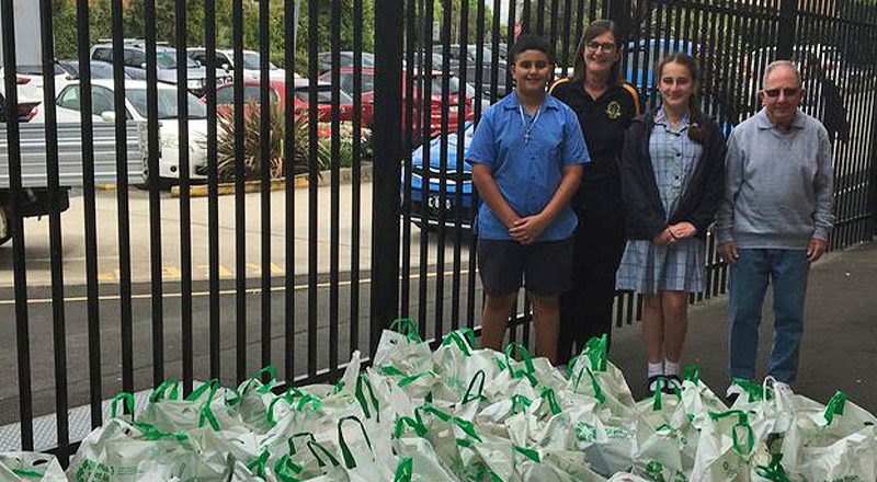 Students standing next to groceries to be donatedfrom Our Lady of the Rosary Catholic Primary School St Marys