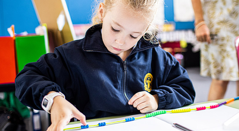 Student learning maths with beads on a string at Our Lady of the Rosary Catholic Primary School St Marys