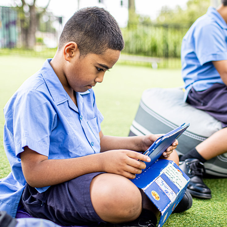 Student outside on iPad at Our Lady of the Rosary Catholic Primary School St Marys