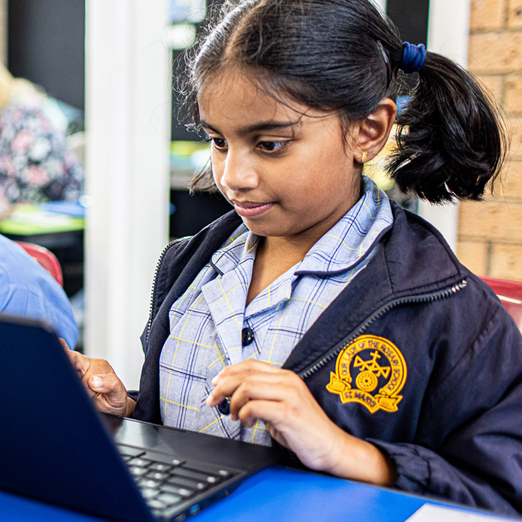 Student smiling on laptop at Our Lady of the Rosary Catholic Primary School St Marys